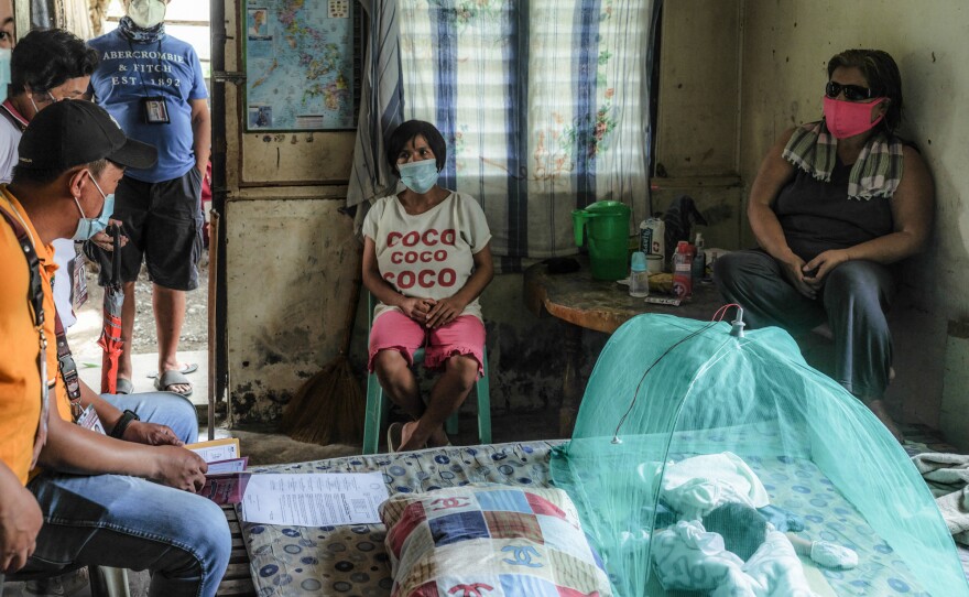 Members of the Bambang health unit question Jessa Tayombong (center) about the home birth of her daughter, Josie, on July 14, which goes against government policy. At right is neighbor Jelina Campoy, who assisted with the birth.