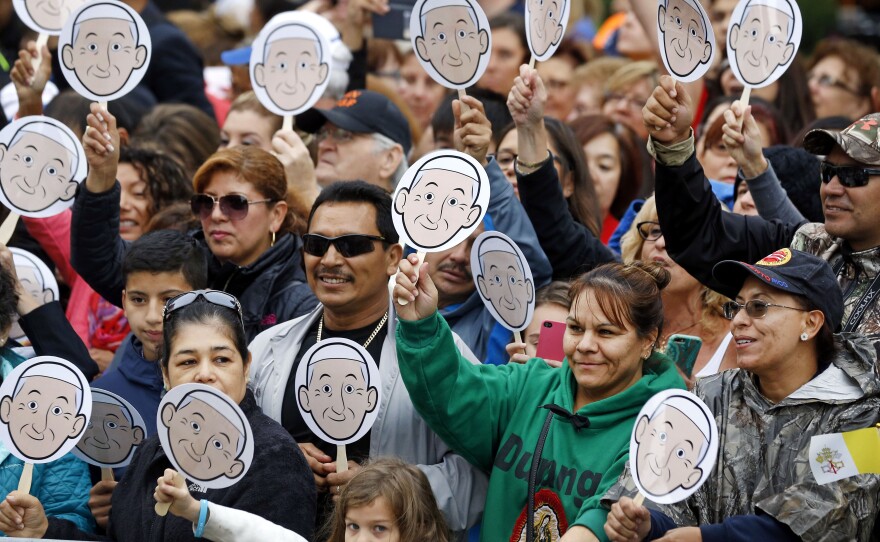 People wave images of Pope Francis as they wait for him to arrive for a Mass at the Cathedral Basilica of Saints Peter and Paul in Philadelphia, on Saturday.