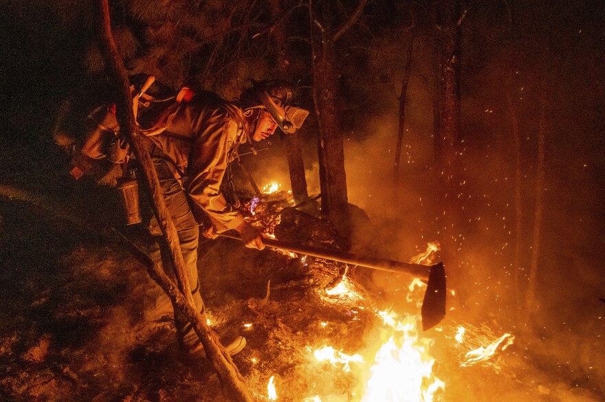 Firefighter Christian Mendoza manages a backfire, flames lit by firefighters to burn off vegetation, while battling the Mosquito Fire in Placer County, Calif., on Tuesday, Sept. 13, 2022.