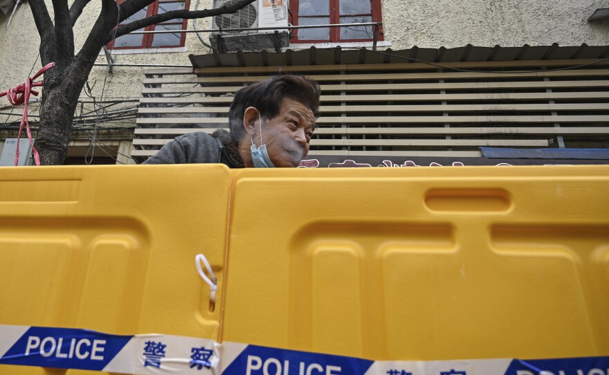 A man stands behind barriers during Shanghai's current COVID lockdown. The speed at which the lockdown was announced left the city's residents scrambling to secure food and supplies.
