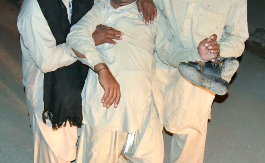 Two men comfort a mourner after the killing of his relative at the shrine Thursday.