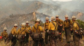 Firefighters take a break Monday near the suburb of Glendale on the outskirts of Los Angeles. Since erupting Aug. 26, the Station Fire has destroyed more than five dozen homes and forced some 12,000 residents to flee.