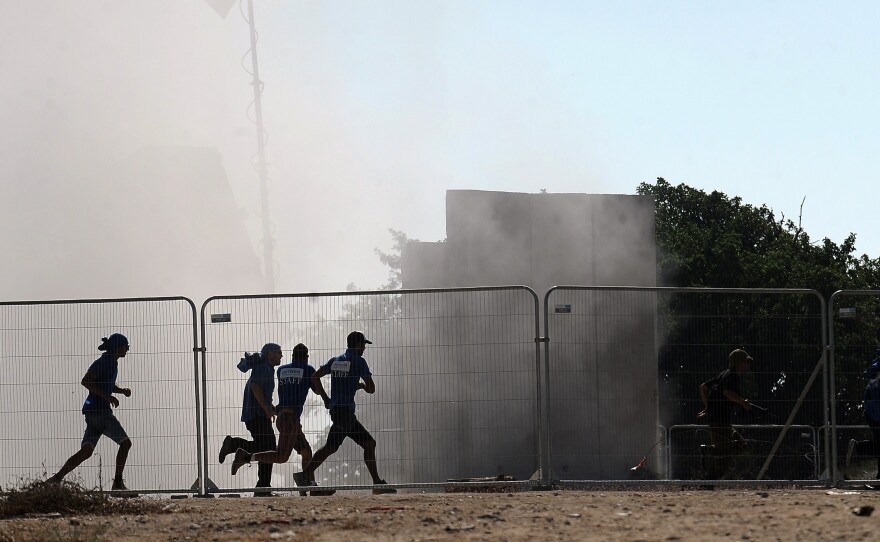 Israelis run for cover seconds after the Iron Dome system, shown in the background,  fired an anti-rocket missile near the southern city of Ashkelon on Aug. 26. Israel developed the Iron Dome system itself and has used it to defend against Palestinian rockets from the Gaza Strip.