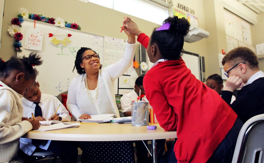 Third-grade teacher Delicia Washington high-fives one of her students during a group exercise at St. Marcus.