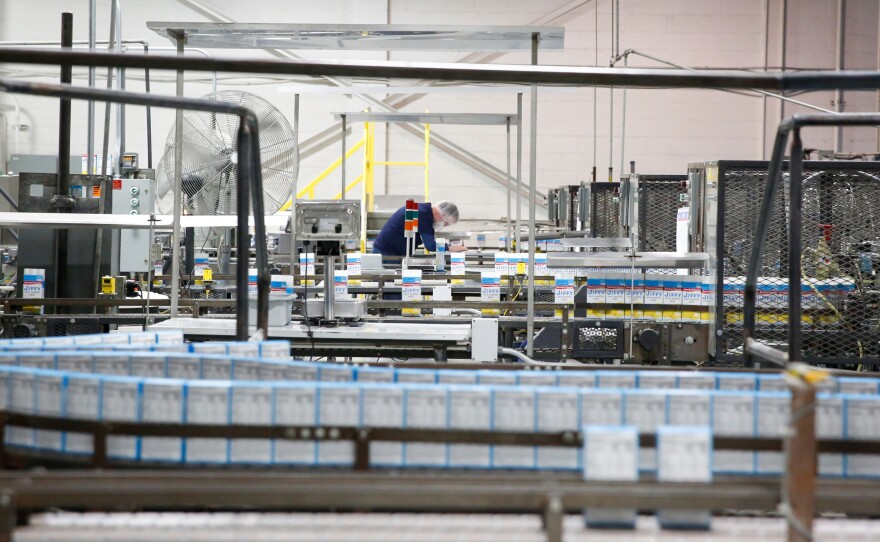 Scenes from the factory floor. (Top left) Filled and sealed boxes of corn muffin mix on a conveyor. (Top right) When boxes are filled with corn muffin mix, an extra little burst of golden mix shoots up into the air. (Bottom) A factory worker checks boxes after they've been filled with mix.