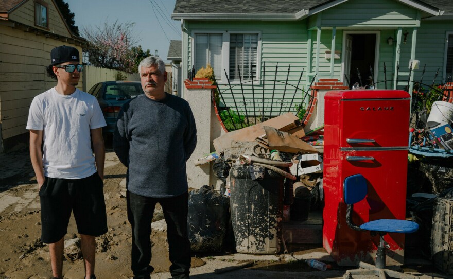 Armando Alvarado, 22, and his father Jesús Valtierra, 52, stand outside their home in Pajaro, California on March 24, 2023. Alvarado worries about how costs to repair the damage will affect his family's rent in a place where a one-bedroom apartment can cost as much as $2,800.