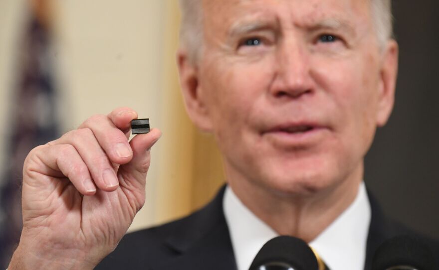 President Biden holds a microchip before signing an executive order on securing critical supply chains in February. A shortage of chips after a surge in demand hampered key sectors such as carmakers.