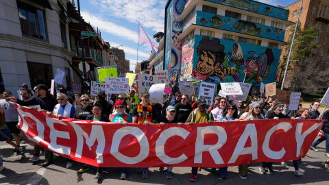 Demonstrators march through the Country Club Plaza shopping district during a "No Kings" protest Saturday, March 28, 2026, in Kansas City, Mo.