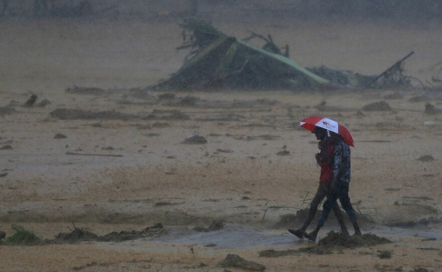 People walk toward safety during a minor landslide following heavy rains in Elangipitiya village in Aranayake, Sri Lanka, on Wednesday. Soldiers and police used sticks and bare hands to dig through mud covering houses in three villages hit by landslides in central Sri Lanka.