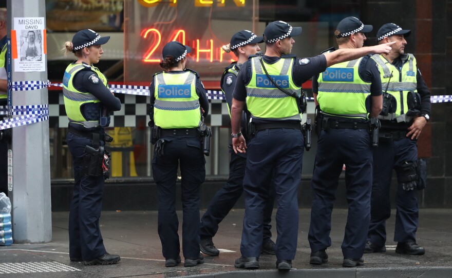 Police are seen in Bourke St. on Friday in Melbourne, Australia. A man was shot by police after setting his car on fire and stabbing three people and killing one in the city's central business district.