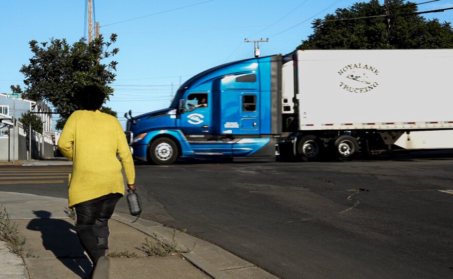 A semi-truck passes by a pedestrian walking through the West National City neighborhood within a half mile from a proposed fuel transfer station on Oct. 24, 2024.
