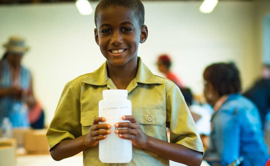 West Philadelphia resident Suliemon Mellette, age 9, stands with an empty test bottle at a recent training at Drexel University’s Dornsife Center. The bottle was sent from Virginia Tech to the citizen-led group, Philly Unleaded Project, as part of a city-wide campaign to test citizen’s drinking water.