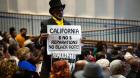 Morris Griffin holds up a sign at the Reparations Task Force hearing at the March Fong Eu Secretary of State offices in Sacramento on June 29, 2023.