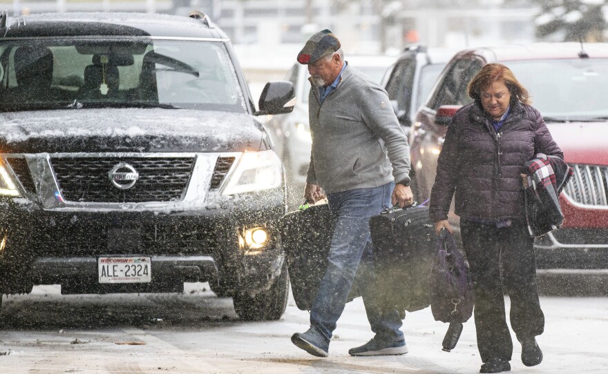 Travelers walk through the snow into Terminal 1 Wednesday, Dec. 21, 2022 at the Minneapolis-Saint Paul International Airport in Minneapolis.