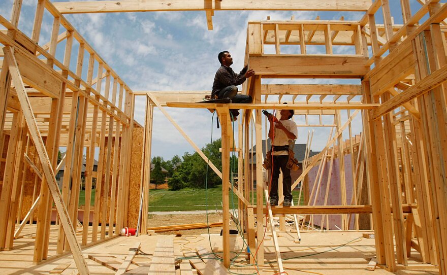 Construction workers frame a house in Louisville, Ky. New construction and existing home sales dropped in June.