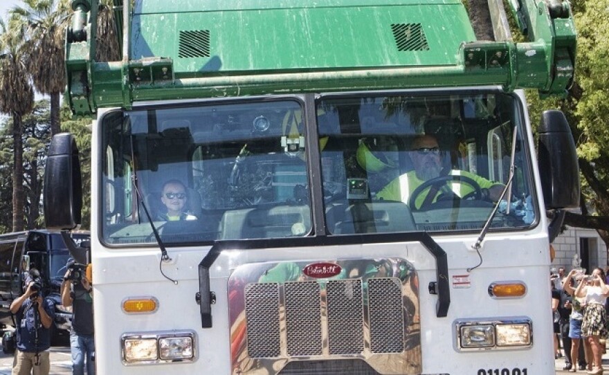 Dean rode in a green garbage truck that had a sign saying "Ethan's Garbage Truck" as part of a parade organized by the Make-a-Wish Foundation and local sponsors.