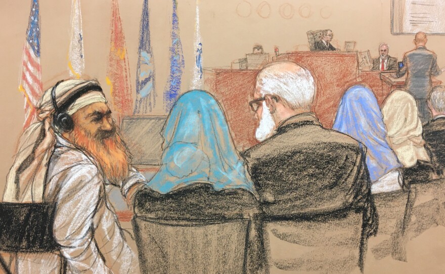 Alleged Sept. 11 mastermind Khalid Sheikh Mohammed (far left) consults with his defense attorneys in the U.S. military courtroom in Guantánamo Bay, Cuba, as a man who waterboarded him, retired Air Force psychologist James Mitchell, takes the stand.