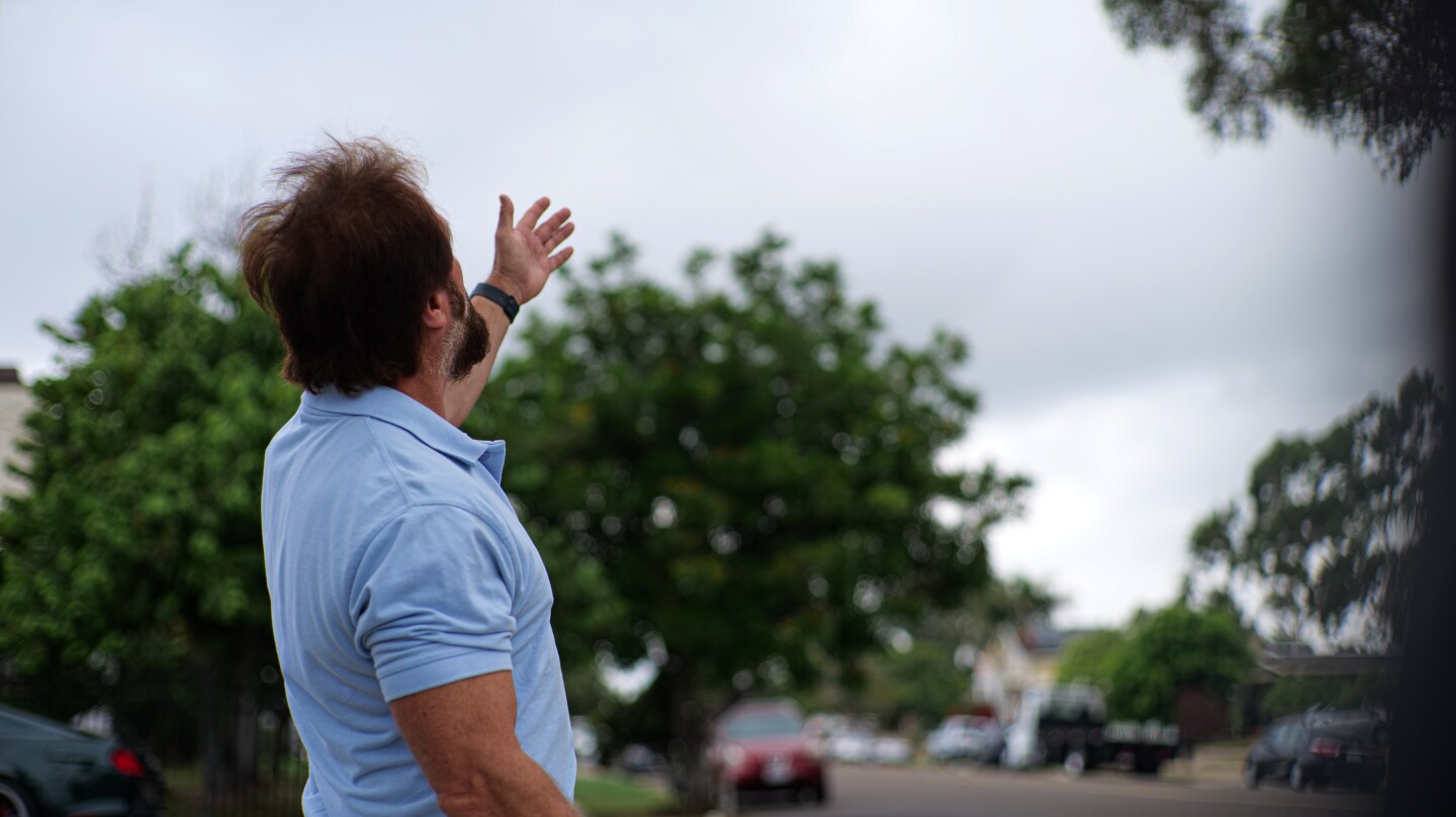 North Park resident Mike Bagnas gestures toward the sky while describing what he saw on the morning of September 25, 1978 in this photo taken in North Park in Sept. 19, 2023.