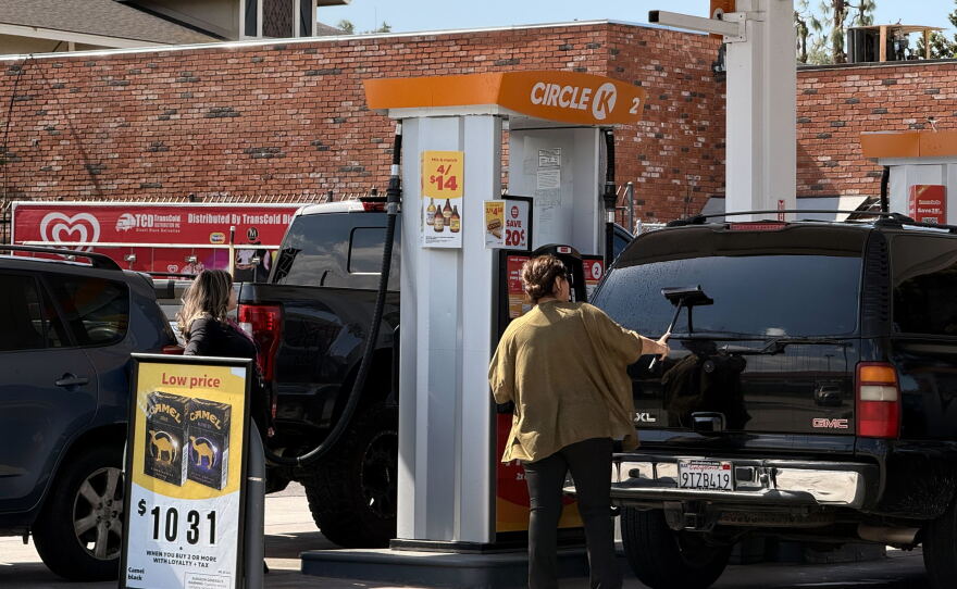 A woman cleans her windshield as another woman pumps gas at a Circle K gas station in Chula Vista, March 5, 2026.