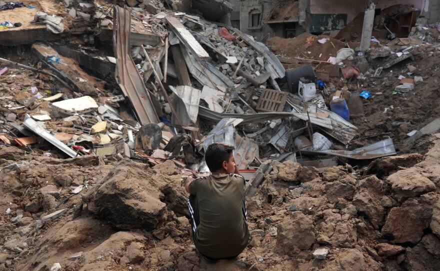 A Palestinian boy sits near the rubble of a residential building destroyed in an Israeli strike in Al-Zawayda in the central Gaza Strip on Saturday.