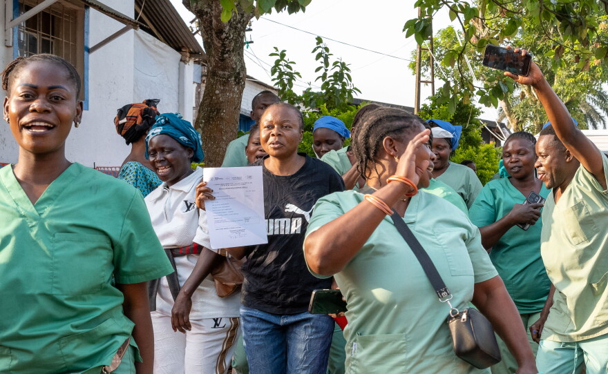 Healthcare workers celebrate the recovery and discharge of Ebola survivor Florence Mangembo, in blue jeans, at the Mongbwalu General Referral Hospital. She is the hospital's bookkeeper.
