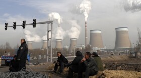 Workers take a break in front of the cooling towers of a coal-fired power plant in Dadong, Shanxi province, China. At a House hearing on Tuesday, Nisha Biswal defended USAID's programs in China, saying the money goes to efforts that include reducing harmful emissions from the country's power plants.