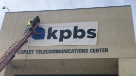 A worker places a banner of the new KPBS logo above the entrance to the KPBS studios, San Diego, Jan. 11, 2019. 