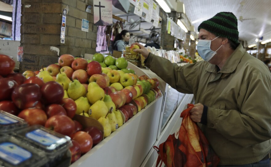 Rick Wittenmyer shops for groceries at the West Side Market, Friday, April 10, 2020, in Cleveland. There were fewer shoppers this year before the Easter holiday than in previous years due to the coronavirus.
