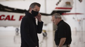California Gov. Gavin Newsom, left, prepares to speak as Mark Ghilarducci, director of the California Governor's Office of Emergency Services, walks past him as Newsom visits the California Department of Forestry and Fire Protection's McClellan Reload Base to discuss the state's new efforts to protect emergency personnel and evacuees from COVID-19 during wildfires. 
