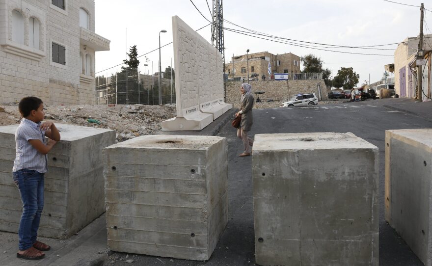 Palestinians look at a new concrete wall erected by Israeli security forces in the East Jerusalem neighborhood of Jabel Mukaber in Jerusalem.