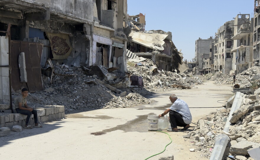 A man fills a jug from from a rigged waterline in al-Shujaiya, but the nearest source of potable drinking water is 30 minutes away.