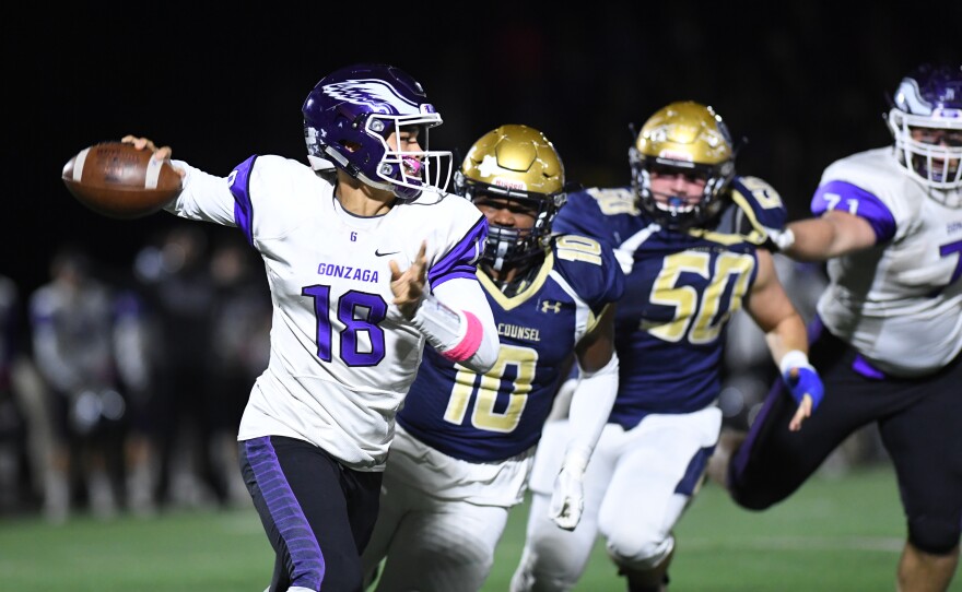Gonzaga quarterback Caleb Williams (18) rolls out against Good Counsel linebacker Jalen Green (10) during a high school game.