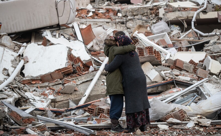 Women hug each other near a collapsed building in Hatay, Turkey on Tuesday.