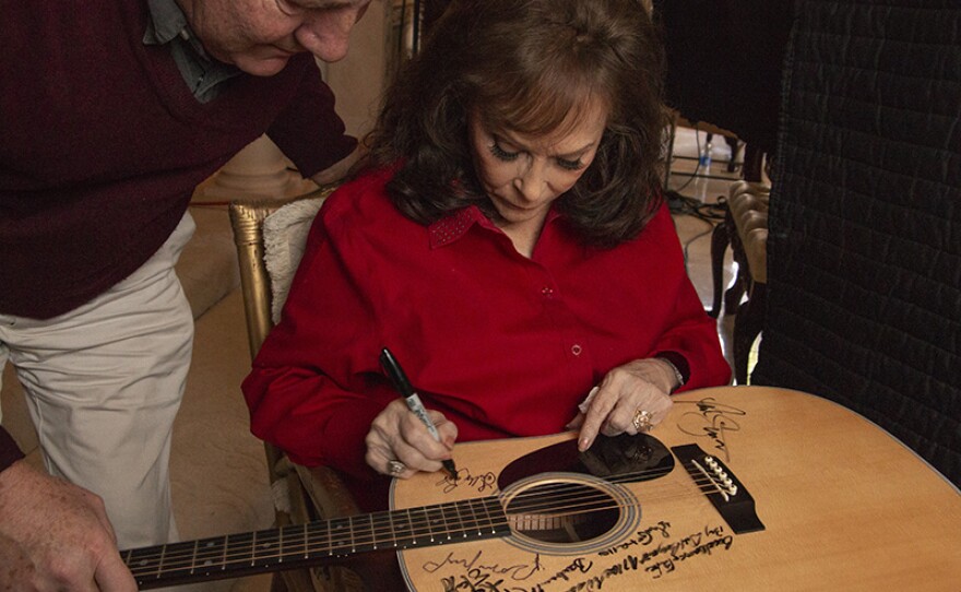 Loretta Lynn signs Martin D-28 guitar. Lynn is among the 76 of the 101 country music artists interviewed for the series who signed two Martin D-28 guitars.