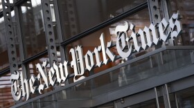 In this Thursday, May 6, 2021 file photo, a sign for The New York Times hangs above the entrance to its building, in New York.