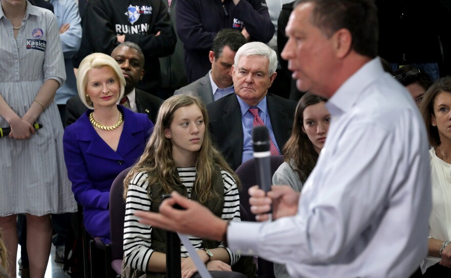 Republican presidential candidate John Kasich addresses an audience, including former Speaker of the House Newt Gingrich (second from right) and his wife, Callista Gingrich, during a town hall-style meeting at George Mason University Law School in Fairfax, Va.