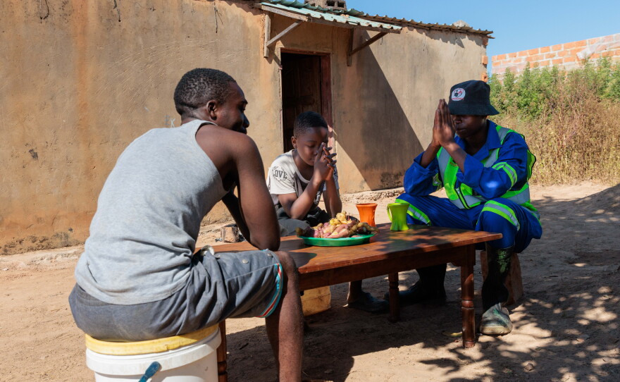 Brothers Joseph, Alumbwe and Gift pray before sharing a meal.