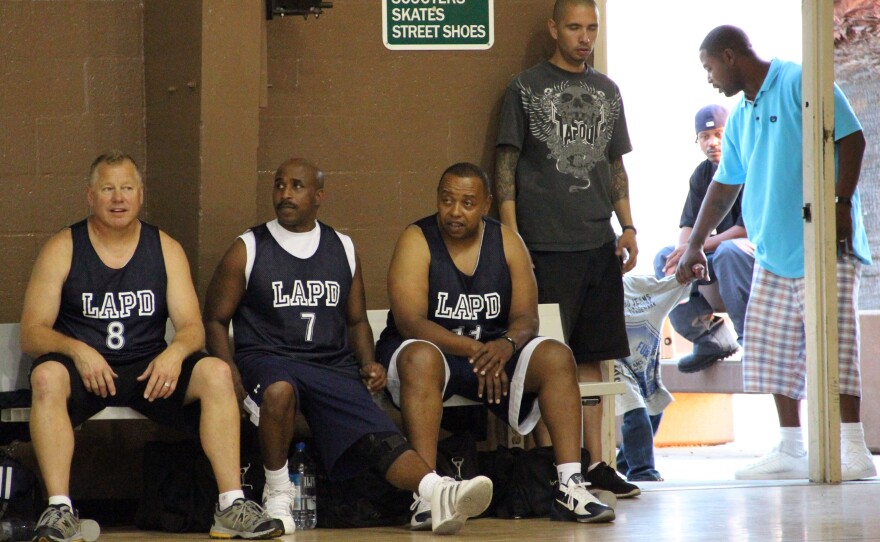 Los Angeles police officers take a break during a basketball game with residents of the Nickerson Gardens housing project in July 2011. Violent crime at Nickerson Gardens and two nearby housing projects has fallen by almost half since 2010.
