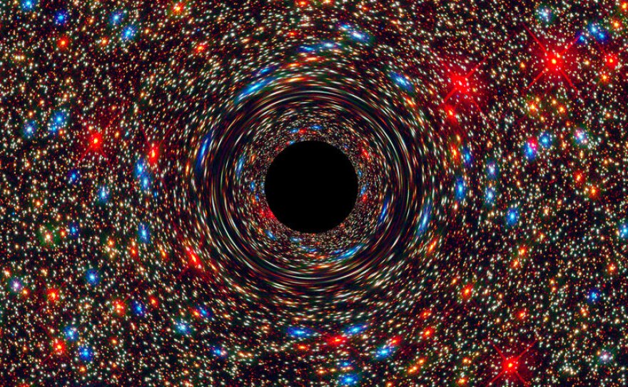 This computer-simulated image shows a supermassive black hole at the core of a galaxy. The cosmic monster's powerful gravity distorts space around it like the mirror in a fun house, smearing the light from nearby stars.