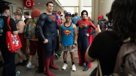 Dan Richard (left) and Carmen Estrada (right), cosplaying Superman and Superwoman, take a photo with Clark Pagauan on July 25, 2025.