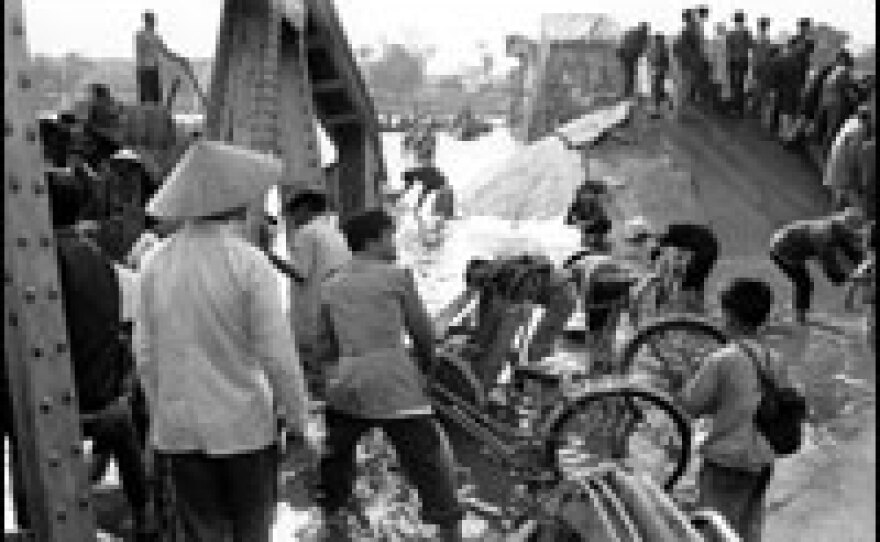 Refugees try to cross the broken bridge over Perfume River in Hue. The bridge was blown up by the North Vietnamese and Viet Cong in February 1968.