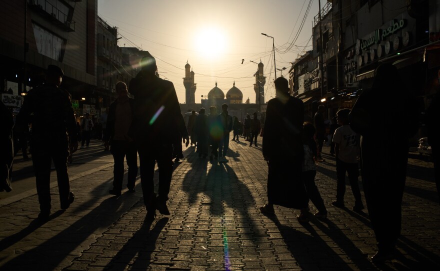 People walk toward the Kadhimiya Shrine at sunset in the Shia neighborhood in Baghdad, Tuesday.