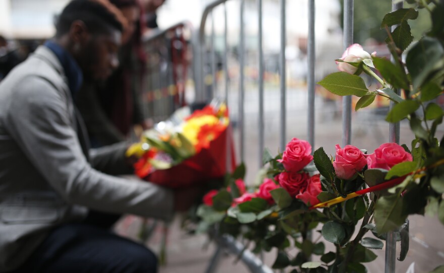 A man places flowers outside the scene of the fire.