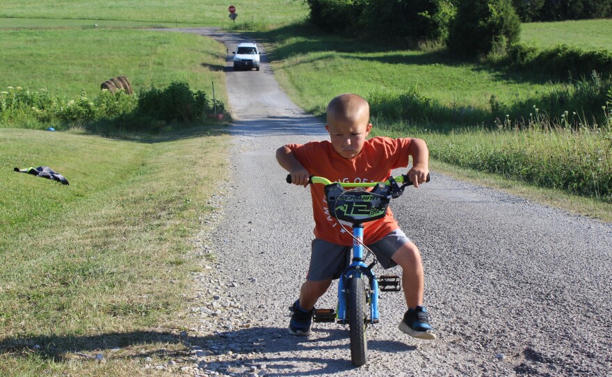 Mason Lester rides a bicycle on a country road in Belfast, Tenn., in June. Mason suffered a broken wrist and arm while uninsured.