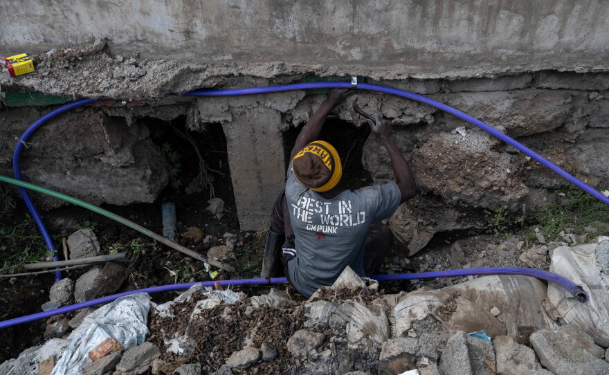 A member of a water cartel in the slum community of Kibera, hammer in hand, cuts into a municipal water pipe to siphon off water illicitly. That water is then sold to residents who aren't able to get government-supplied water.
