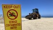 A front loader moves sand near the Imperial Beach pier while the water is off-limits to swimming and surfing on Jun. 21, 2023