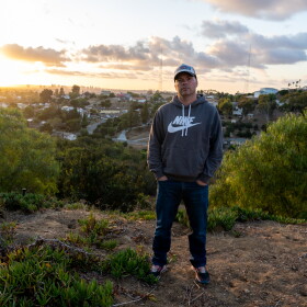 Encanto resident Rob Campbell stands in his backyard on Tuesday, Oct. 29, 2024. Behind him, radio towers mark the site of a future housing development in Emerald Hills.