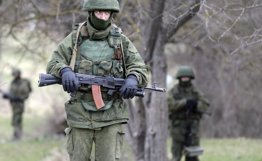 Armed men in unmarked military uniforms — who witnesses believe are Russian troops, but who Russian leaders say are "local self-defense" forces — stand outside the territory of a Ukrainian military unit in the Crimean village of Perevalnoye.