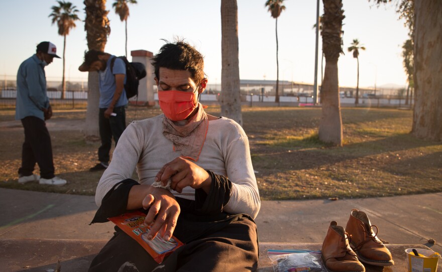 Peter Sanchez, a Navy veteran from Calexico, cleans his hands with wipes handed out by the Brown Bag Coalition in Calexico's Border Friendship Park, April 21, 2020.