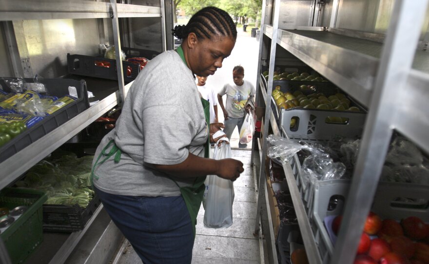 Peaches & Greens driver Diane Brown helps customers out of her truck in Detroit where she sells fresh fruits and vegetables.